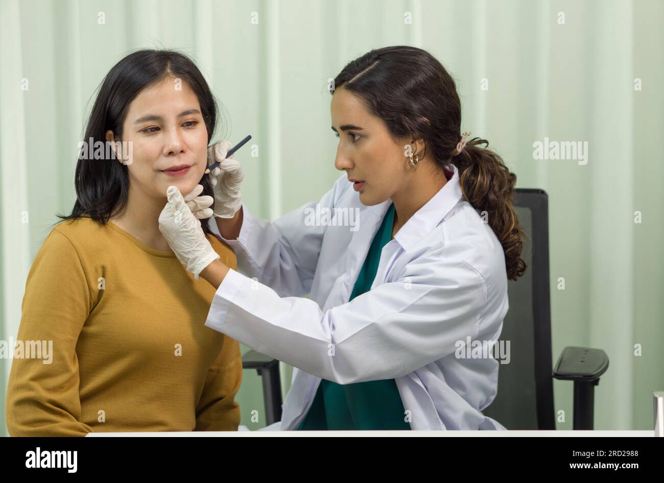 Un professionnel de la santé effectue précisément une procédure de diagnostic du menton sur une patiente dans un environnement clinique désinfecté. Ils ont Banque D'Images