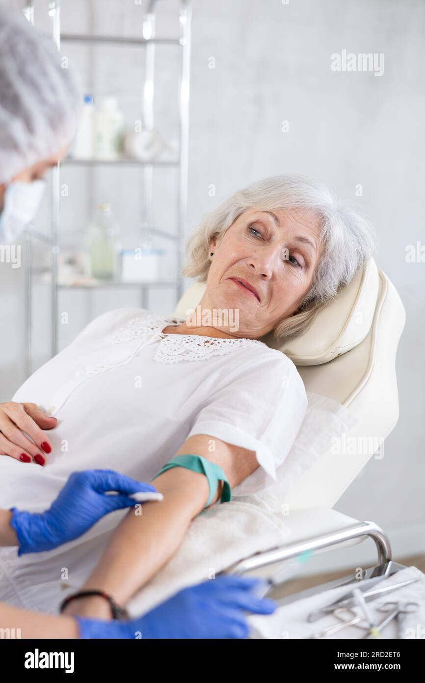 Femme médecin faisant l'injection à la vieille femme fatiguée endormie dans la clinique. Banque D'Images