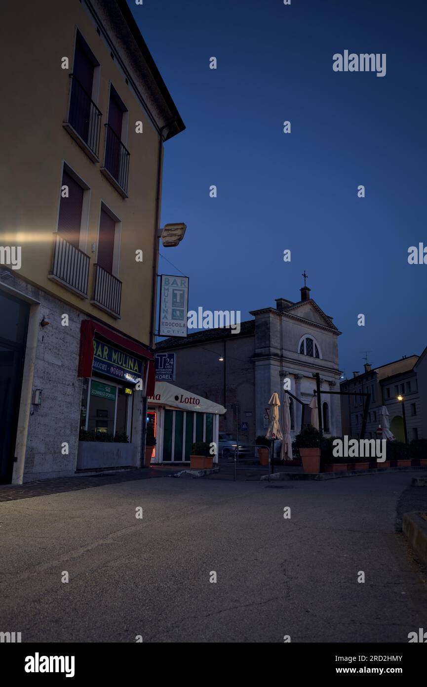 Chaussée devant un groupe de bâtiments et vitrines dans une ville italienne au crépuscule Banque D'Images