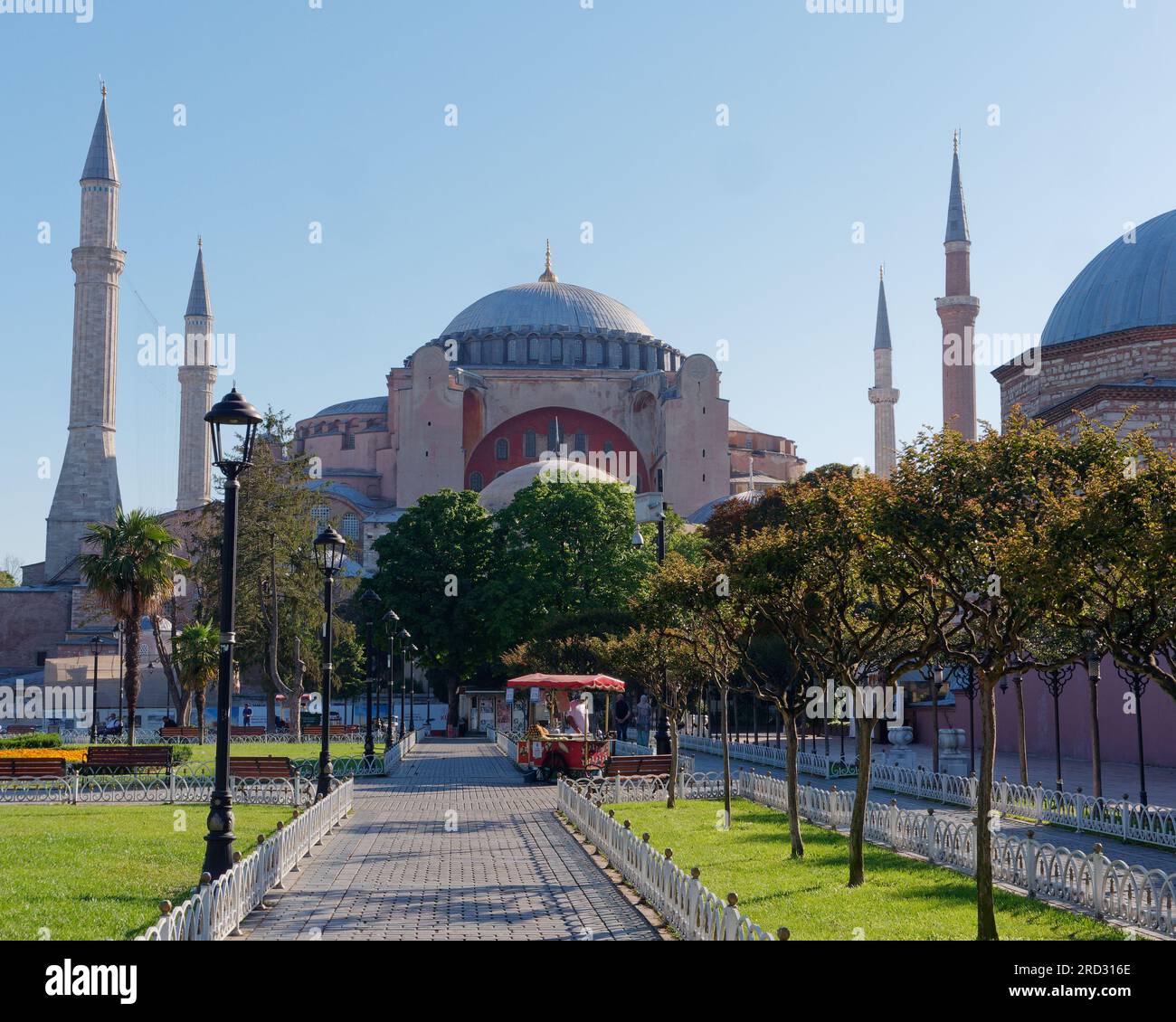 Jardins du parc Sultanahmet avec la mosquée Sainte-Sophie et un hammam droit. Le chariot distributeur rouge vend du maïs rôti. Istanbul, Turquie Banque D'Images