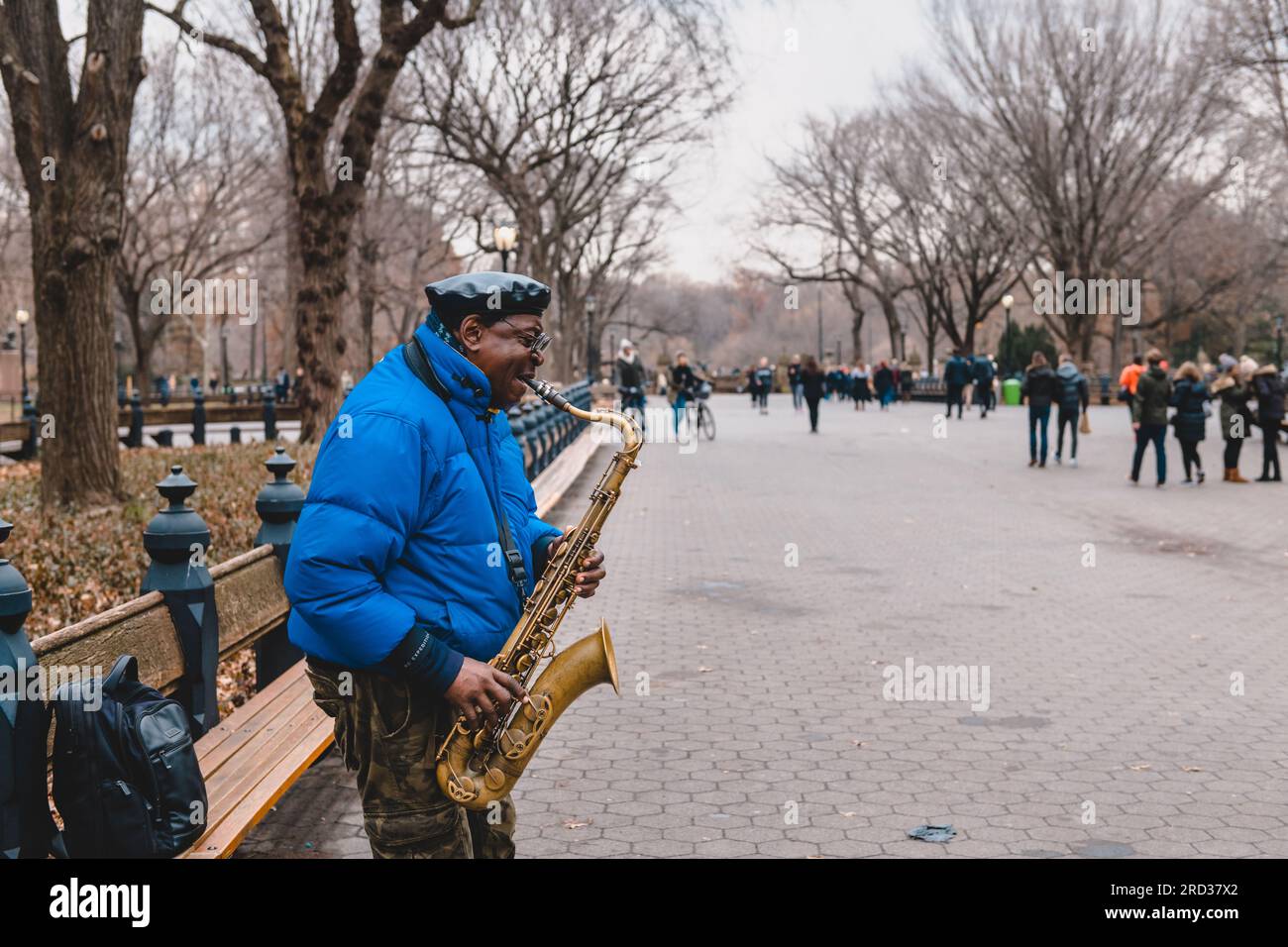Busker jouant du saxophone tandis que d'autres passants passent autour de lui, Central Park, New York Banque D'Images
