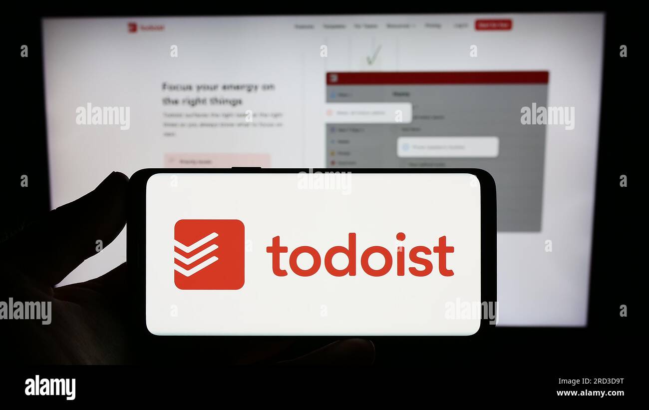 Personne tenant un smartphone avec le logo de la société américaine de gestion des tâches Todoist (Doist Inc.) sur l'écran devant le site Web. Concentrez-vous sur l'affichage du téléphone. Banque D'Images