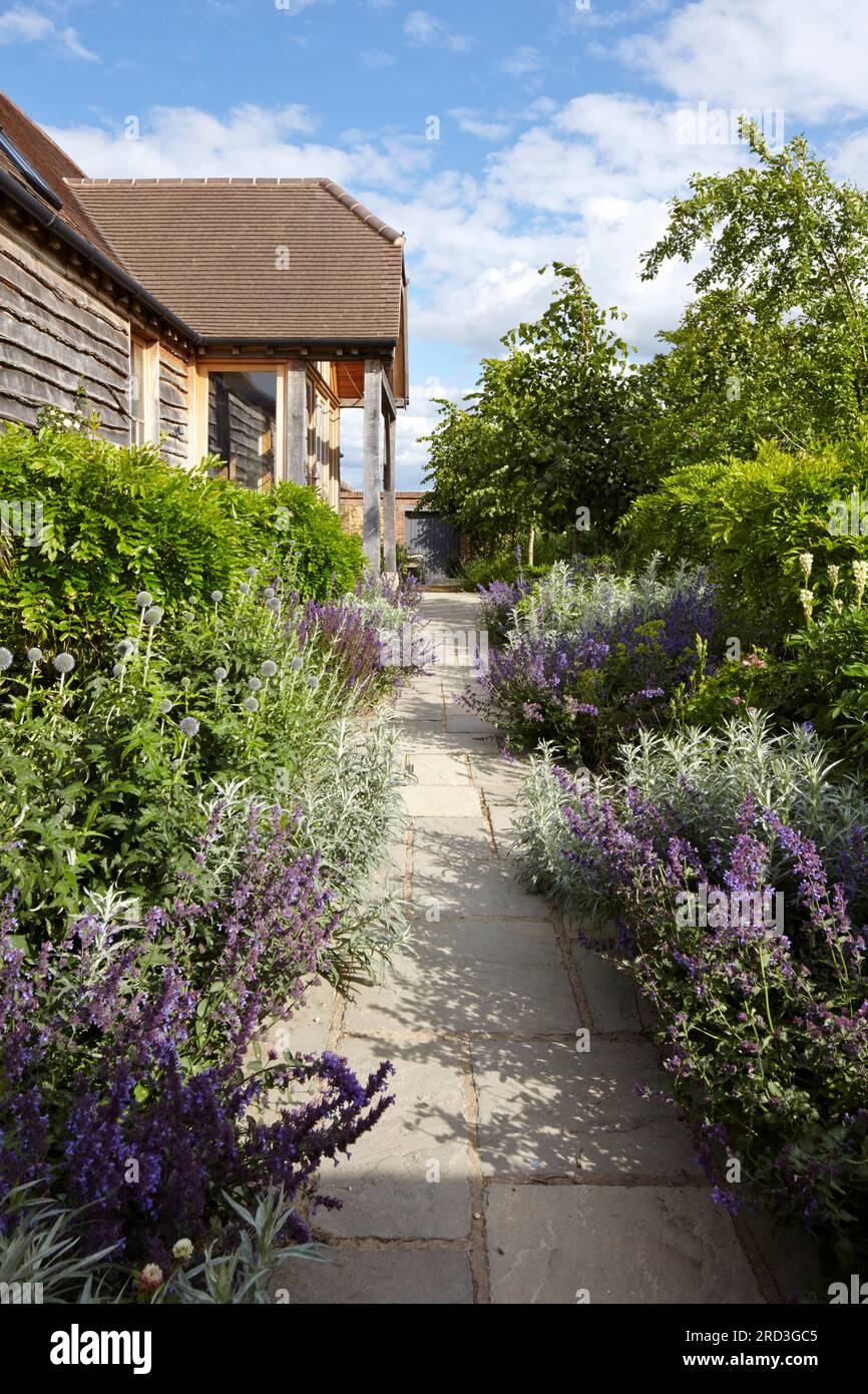 Chemin menant à l'entrée principale avec bordure fleurie de chaque côté. Manor Barn, Faringdon, Royaume-Uni. Architecte : aucun, 2015. Banque D'Images