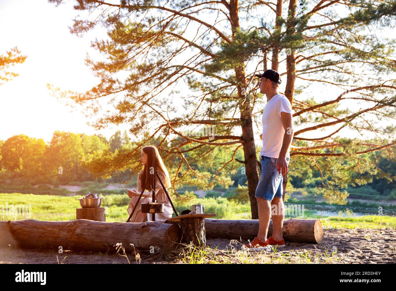 Une jeune fille et un gars se reposent dans la nature en été. Beau paysage sur les rives de la rivière et de la forêt. Pique-nique et tourisme. Banque D'Images
