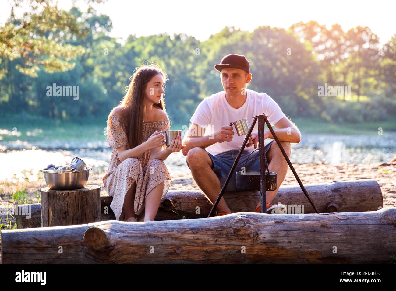 Jeune homme et fille s'assoient sur des bûches dans la nature et communiquent. Loisirs en plein air en été, détente. Banque D'Images