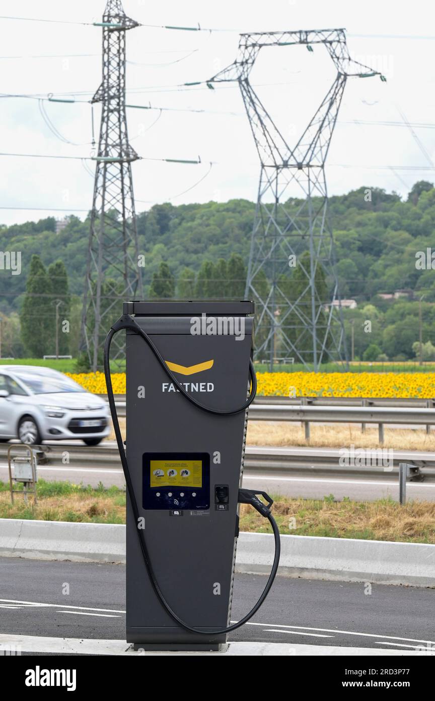 FRANCE, station de recharge rapide pour véhicule électrique à la station de carburant Dyneff sur l'autoroute, derrière le champ de tournesol et poteau de transmission de puissance / FRANKREICH, Fastned Stromladestation für Elektrofahrzeuge an Dyneff Tankstelle an der Autobahn, hintergrund Sonnenblume Feld Banque D'Images