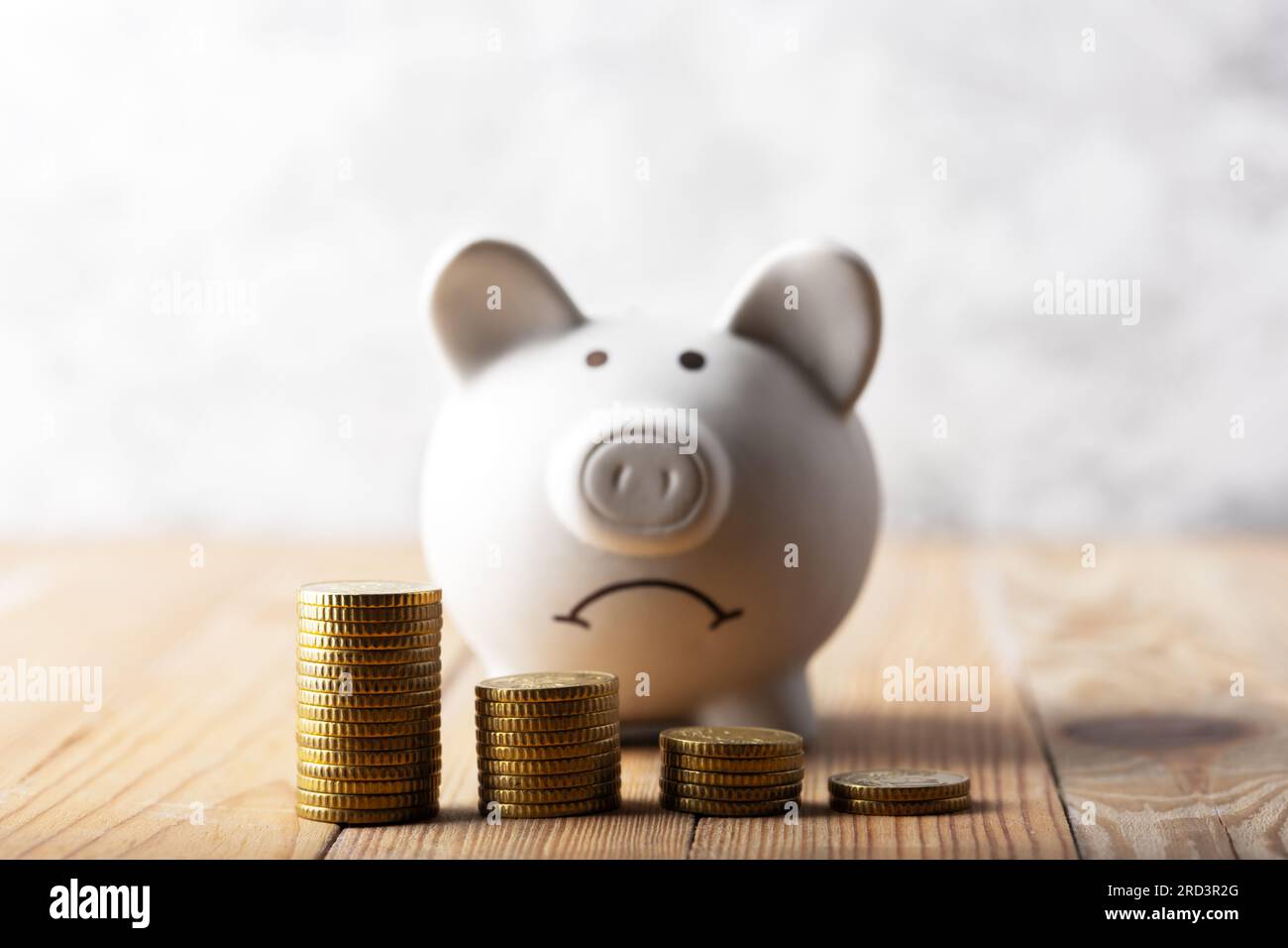 Une triste banque tirade derrière des piles de pièces en euros symbolisant la chute des actifs monétaires. Moneybox blanche avec graphique de pièces. Concept de crise Banque D'Images