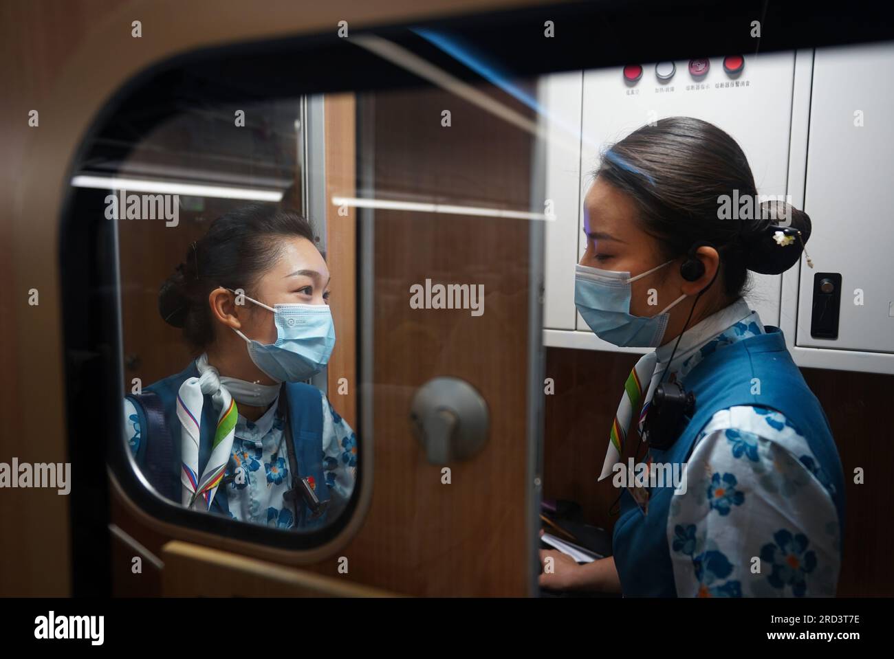 (230718) -- MENGLA, 18 juillet 2023 (Xinhua) -- Yi Bofeng (L) s'entretient avec sa collègue à bord du train D887 le 16 juillet 2023. Yi Bofeng est originaire du comté de Mengla dans la province du Yunnan. Après avoir obtenu son diplôme de major laotien dans un collège technique de la capitale provinciale Kunming en 2020, elle a été recrutée comme hôtesse de train dans China Railway Kunming Bureau Group Co., Ltd Le chemin de fer Chine-Laos, un projet historique de coopération de haute qualité ceinture et route, a commencé ses opérations en décembre 2021. Yi était à bord du premier train du chemin de fer, témoin du moment historique de l'exploitation ferroviaire. TH Banque D'Images