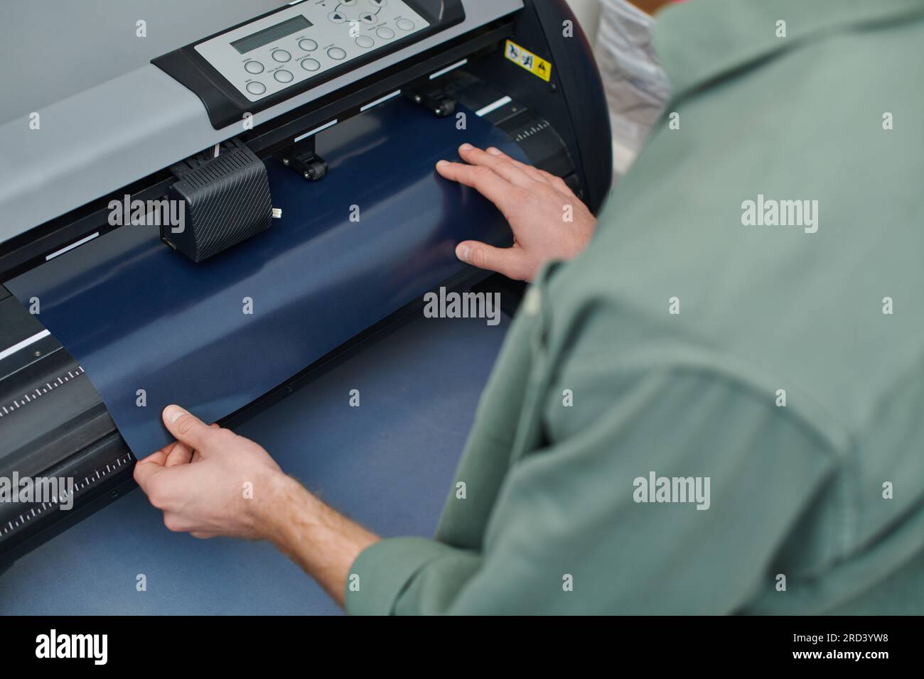 Vue à angle élevé du jeune artisan prenant la couche de la machine de sérigraphie et travaillant dans le studio d'impression, propriétaire de petite entreprise travaillant sur le projet, creat Banque D'Images