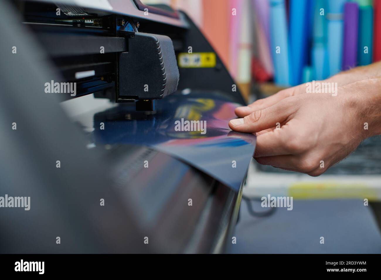 Vue recadrée de jeune artisan tenant la couche près de la machine d'impression d'écran dans l'atelier flou, propriétaire de petite entreprise travaillant sur le projet, proc créatif Banque D'Images