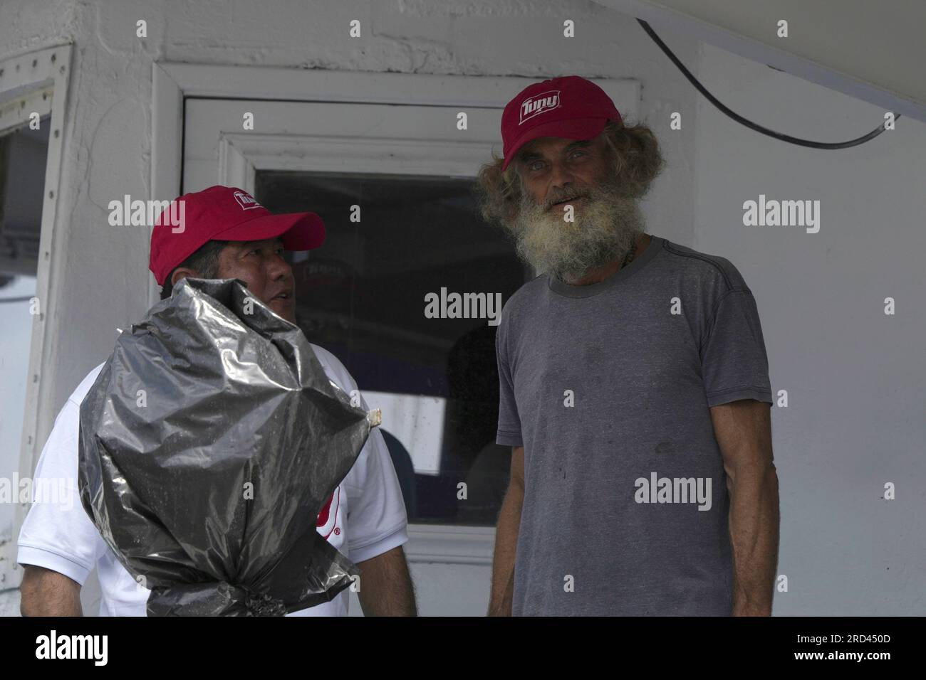 Australian Timothy Lyndsay Shaddock, right, stands next to a crew member of the Mexican tuna boat "Maria Delia," as they arrive to port in Manzanillo, Mexico, Tuesday, July 18, 2023. After being adrift with his dog for three months, Shaddock and his dog Bella were rescued from his incapacitated catamaran in the Pacific Ocean some 1,200 miles from land. (AP Photo/Fernando Llano) Banque D'Images