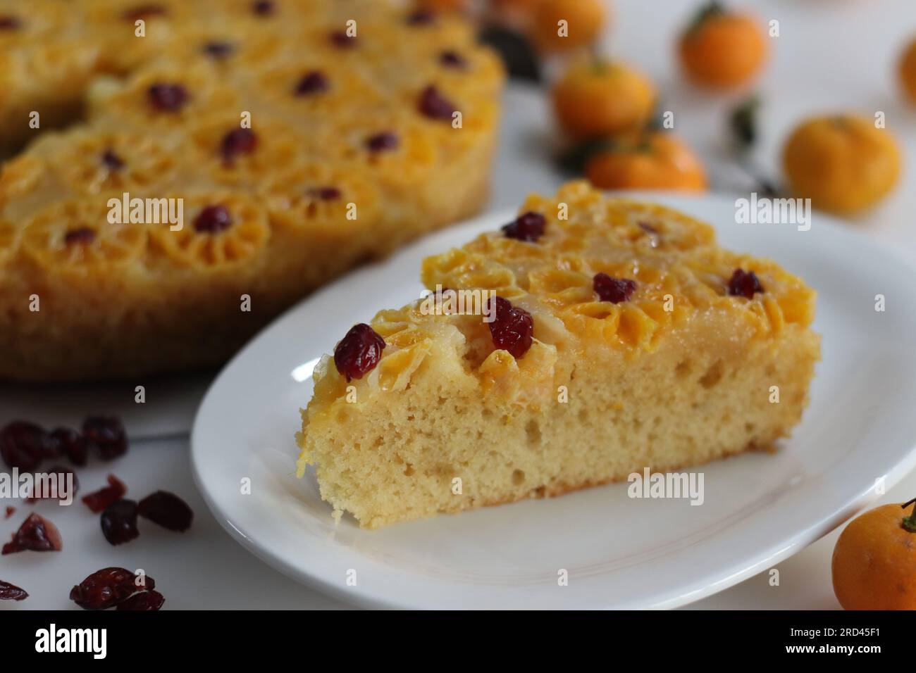 Tranche de gâteau à l'orange à l'envers. Gâteau à l'orange maison à l'envers avec des tranches d'orange bébé ou de clémentine sur le dessus avec des canneberges séchées pour Banque D'Images