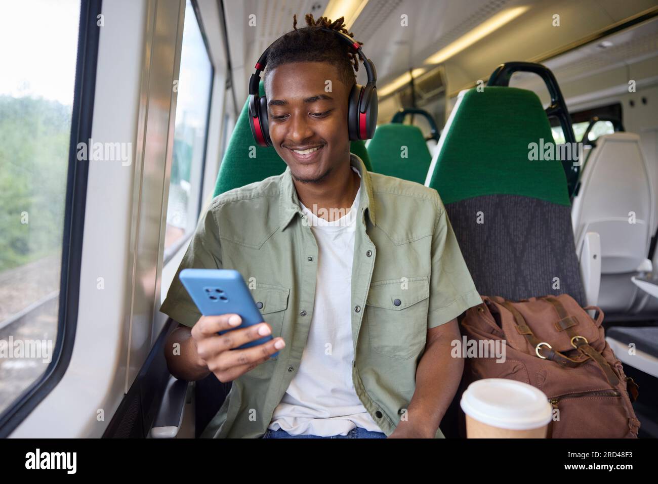 Jeunes hommes se rendant au travail sur le train assis sur le train regardant le téléphone portable pour des informations de voyage ou les médias sociaux Banque D'Images