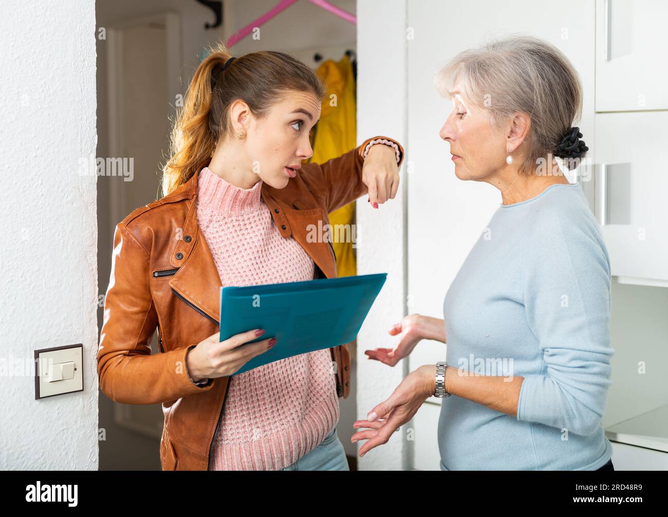 Les femmes collectrices de dette parlaient agacés à une femme âgée inquiète à la maison Banque D'Images