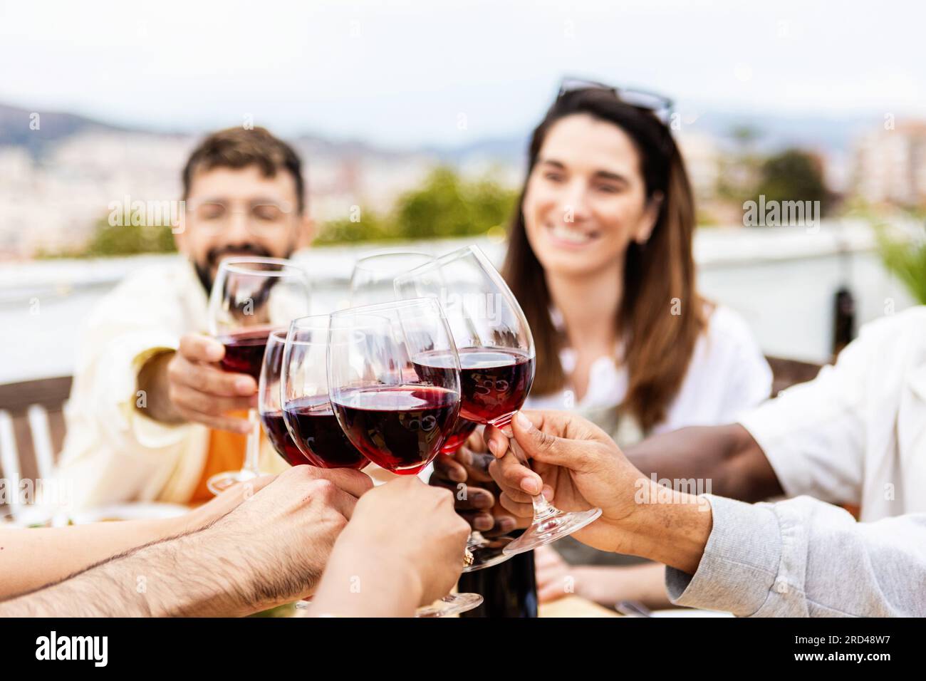 Jeune groupe de personnes buvant du vin rouge à la fête d'été sur le ...