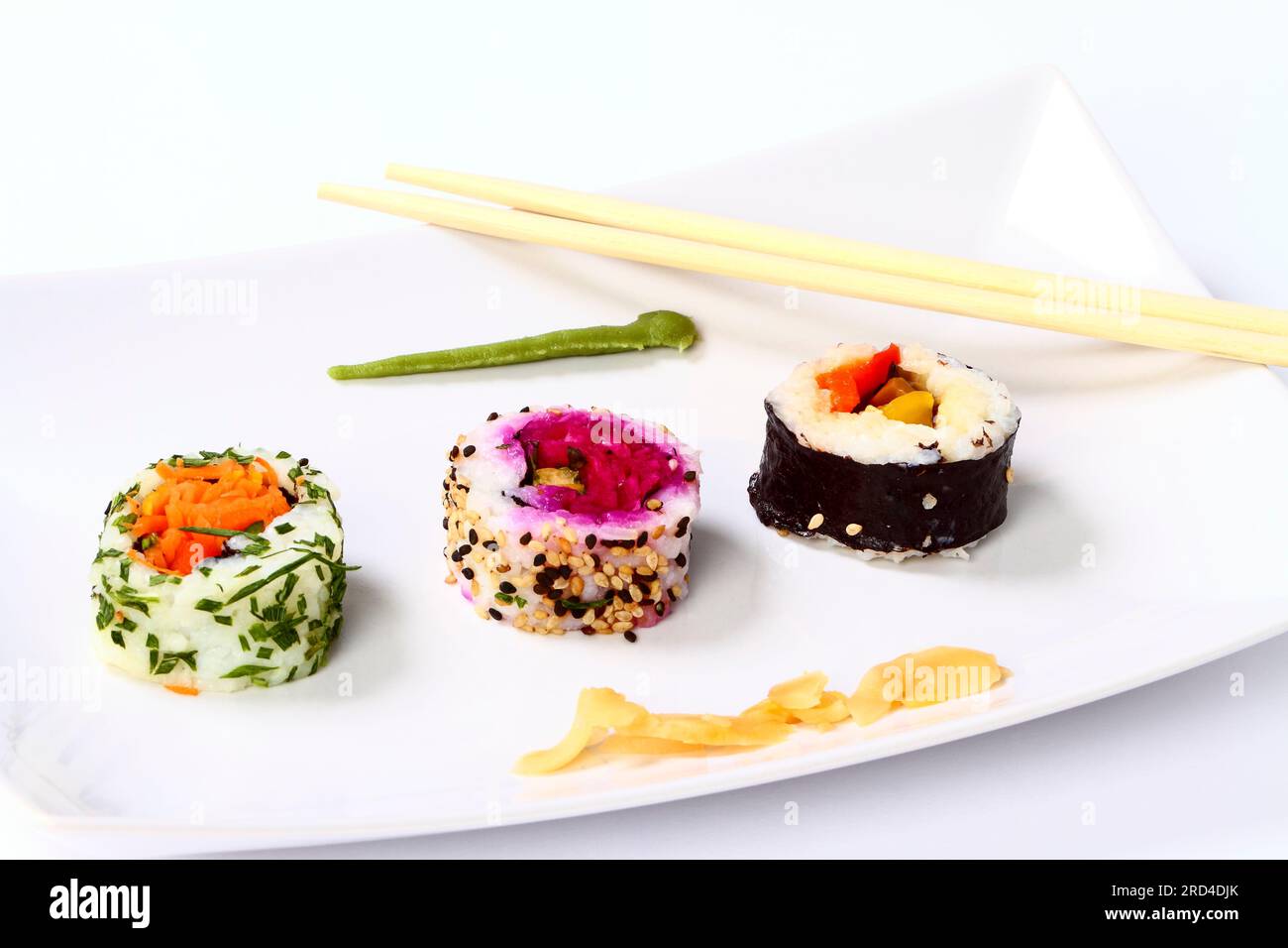 Rouleaux de sushi végétaliens et une paire de baguettes sur une assiette blanche Banque D'Images