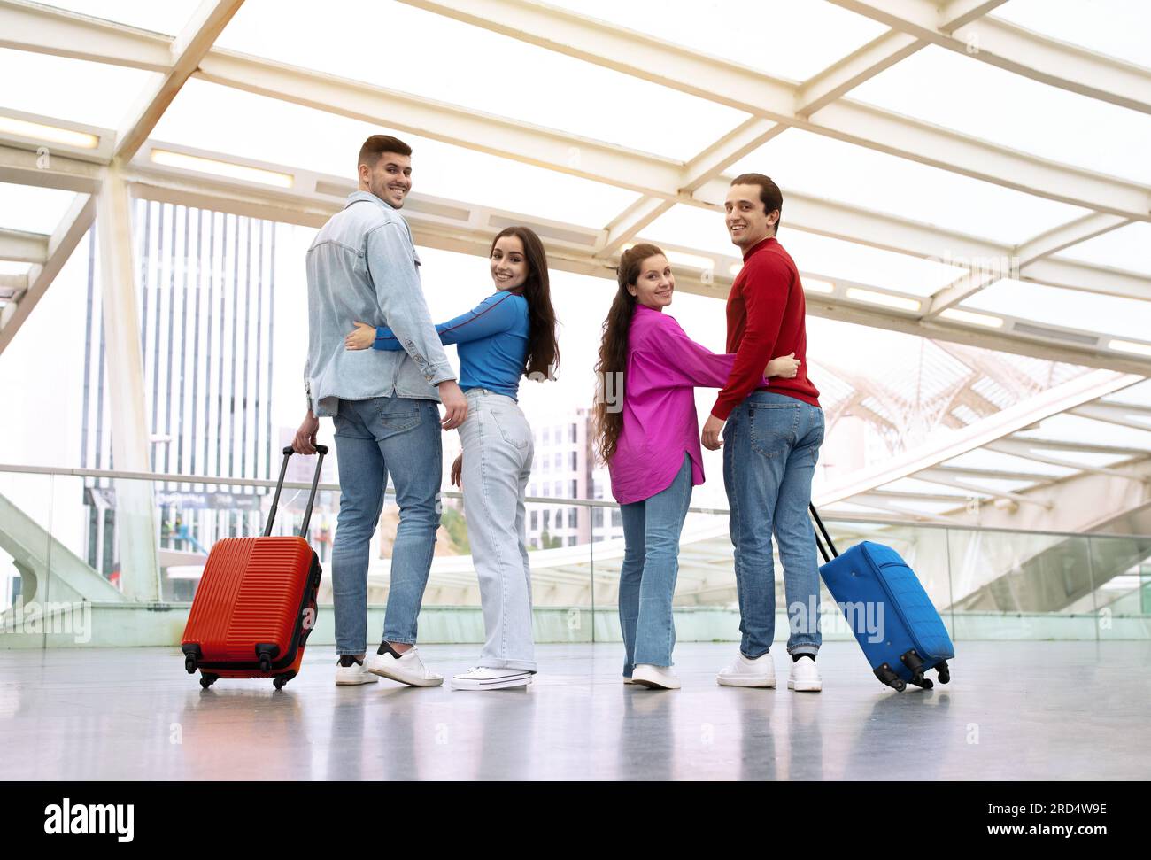 Deux couples romantiques serrant avec des valises dans l'aéroport moderne Banque D'Images