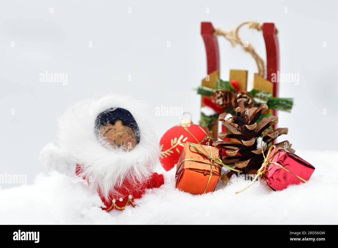 Décoration de Noël, Inuit avec traîneau et boule d'arbre de Noël et pommes de pin et cadeaux de Noël couchés dans la neige Banque D'Images