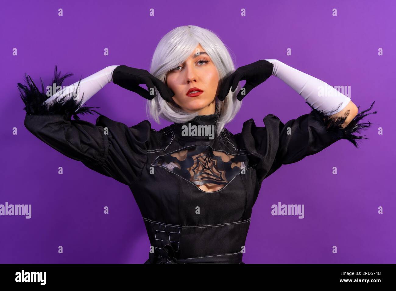 Portrait de femme cosplay dans un costume noir et une perruque blanche en studio sur un fond violet Banque D'Images