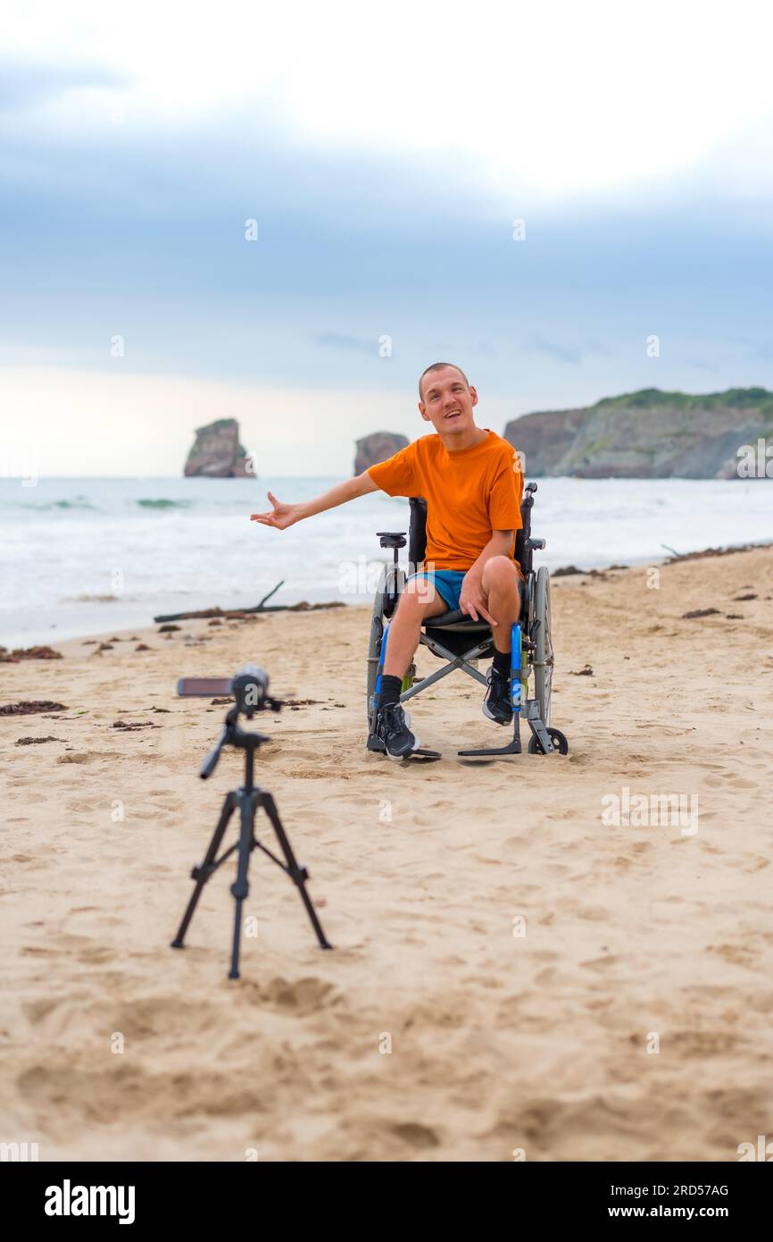 Portrait d'une personne handicapée en fauteuil roulant sur la plage enregistrant un blog vidéo Banque D'Images