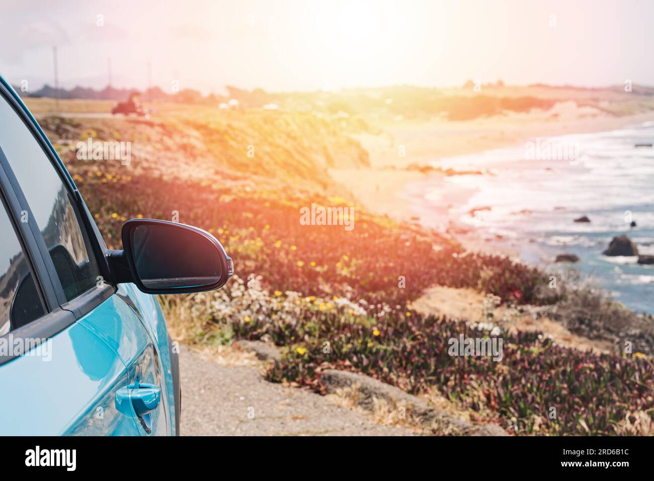 Gros plan du miroir de voiture bleue près de l'océan avec une lueur chaude, concept Road trip Banque D'Images