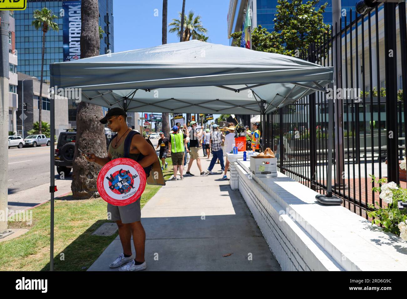 Hollywood, Californie, États-Unis 18 juillet 2023. Un bel homme noir tenant un bouclier Captain America qui dit : « nous pouvons faire ça toute la journée », se réfugie sous une tente devant la ligne de piquetage. Les acteurs hollywoodiens rejoignent Writers (qui frappent depuis deux mois) le deuxième jour de la grève de Screen Actors Guild, devant le siège de Netflix et Sunset Studios à Hollywood, en Californie. Les esprits étaient élevés malgré l'avertissement de chaleur extrême en cours à Los Angeles, et les tempéraments chauds sur la perception de la cupidité de l'entreprise et l'échec des cadres de cinéma et de télévision à répondre à leurs besoins. Banque D'Images