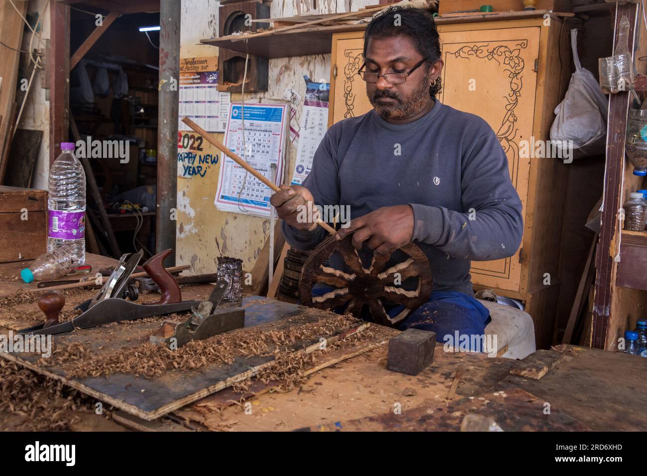 Homme travaillant sur une belle sculpture d'un boutre dans une usine de boutre à sur, Oman Banque D'Images