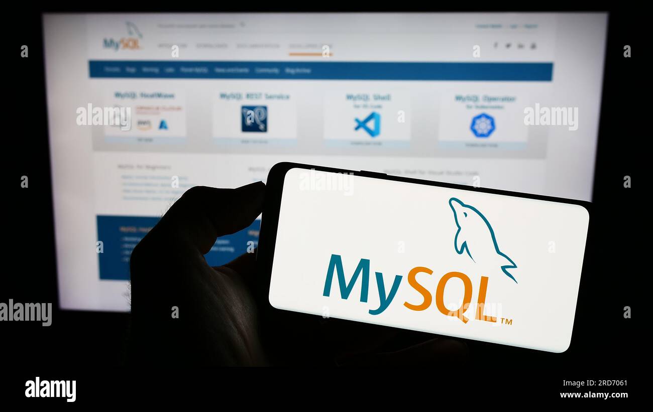 Personne tenant le téléphone portable avec le logo du système de gestion de base de données relationnelle MySQL sur l'écran en face de la page Web. Concentrez-vous sur l'affichage du téléphone. Banque D'Images Personne tenant le téléphone portable avec le logo du système de gestion de base de données relationnelle MySQL sur l'écran en face de la page Web. Concentrez-vous sur l'affichage du téléphone. Banque D'Images