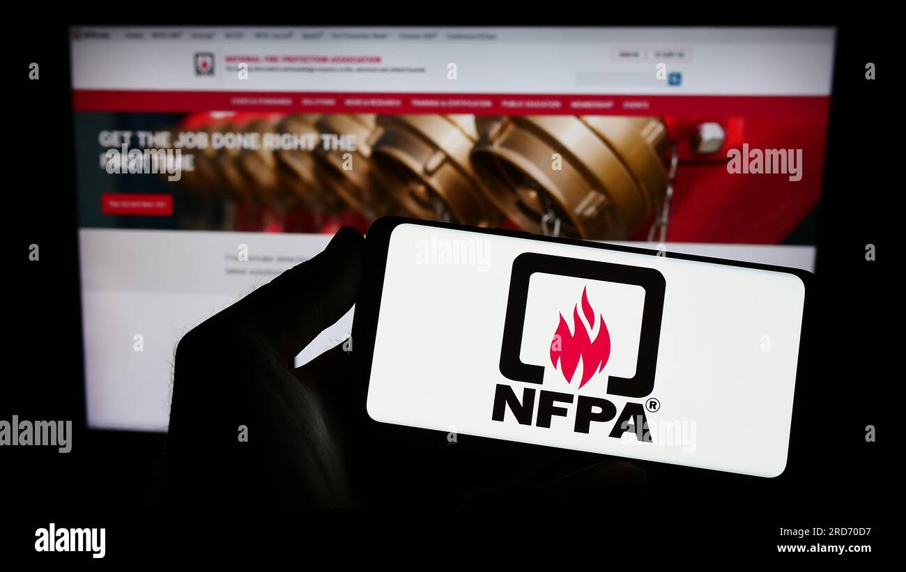 Personne tenant un smartphone avec le logo de la National Fire protection Association (NFPA) sur l'écran devant le site Web. Concentrez-vous sur l'affichage du téléphone. Banque D'Images