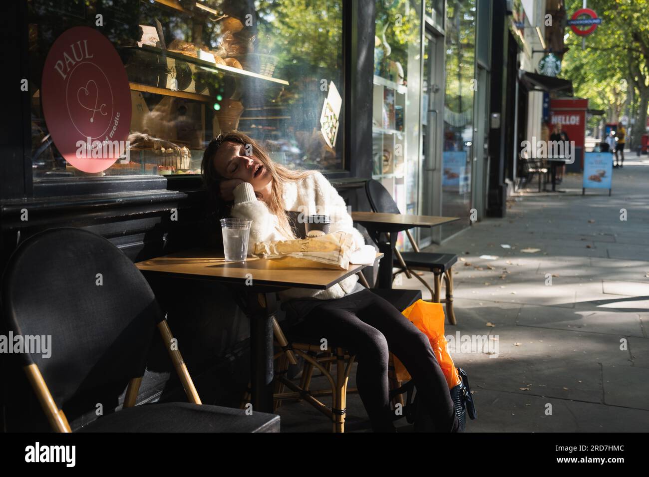 Des femmes séduisantes dans sa vingtaine dorment dehors dans un café à Holland Park Avenue, Londres Banque D'Images