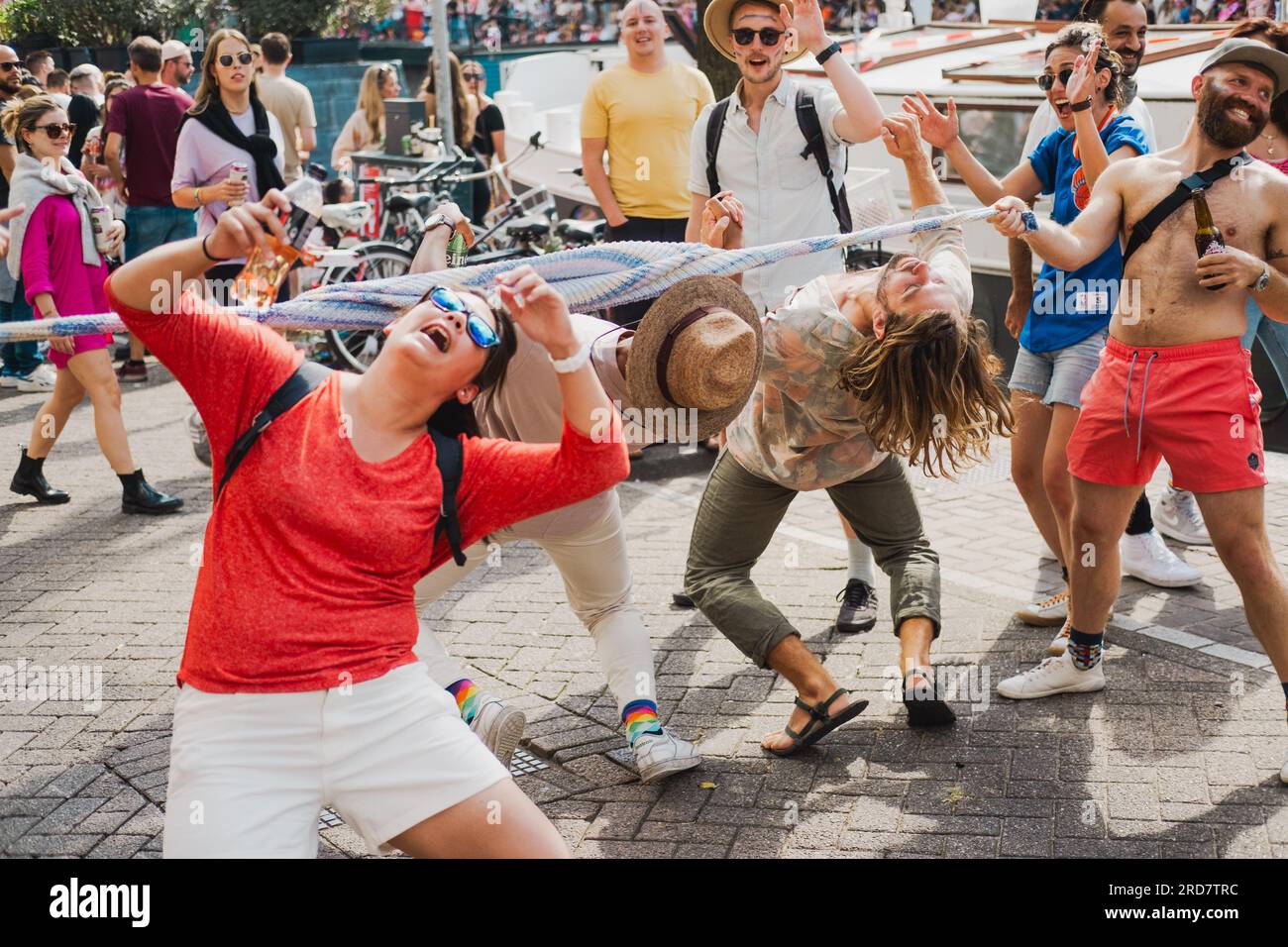 Amsterdam, Hollande du Nord, pays-Bas – 6 août 2022 : les spectateurs dansent impromptue les limbo dans les rues de la ville pour célébrer la parade de la fierté Banque D'Images