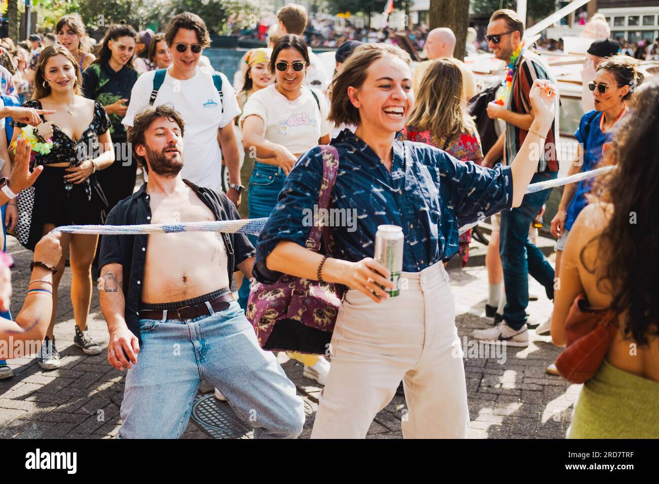 Amsterdam, Hollande du Nord, pays-Bas – 6 août 2022 : une foule de personnes célébrant Pride Amsterdam participent joyeusement à la danse limbo Banque D'Images