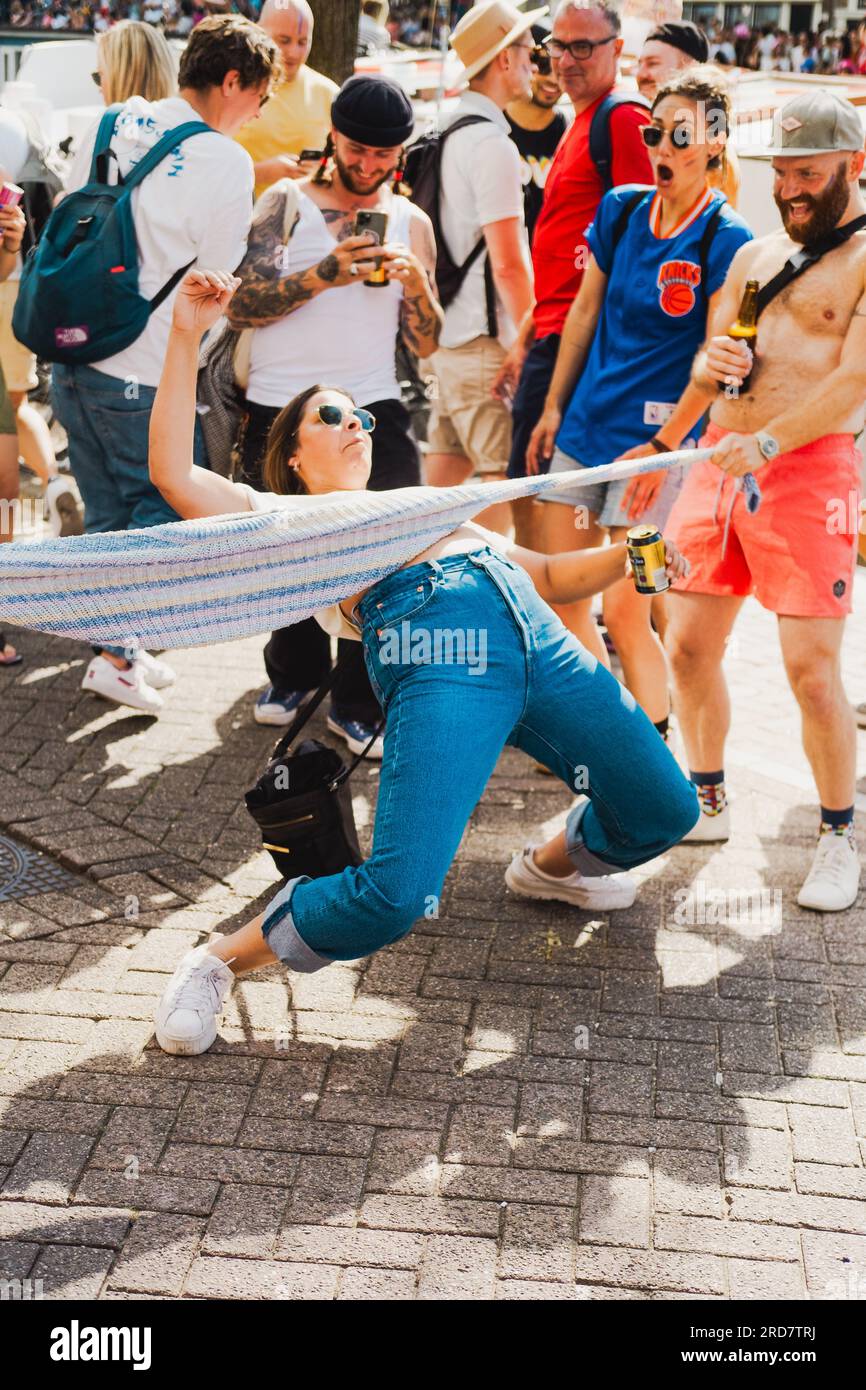 Amsterdam, Hollande du Nord, pays-Bas – 6 août 2022 : une femme fait de la danse limbo dans une rue à une foule de gens acclamant pendant la Pride Amsterdam Banque D'Images