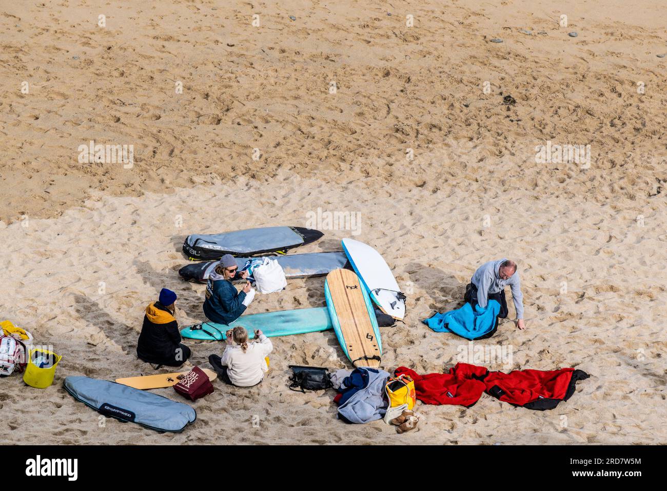 Une vue aérienne d'un groupe de surfeurs assis avec leurs planches de surf sur Tolwan Beach à Newquay en Cornouailles au Royaume-Uni. Banque D'Images