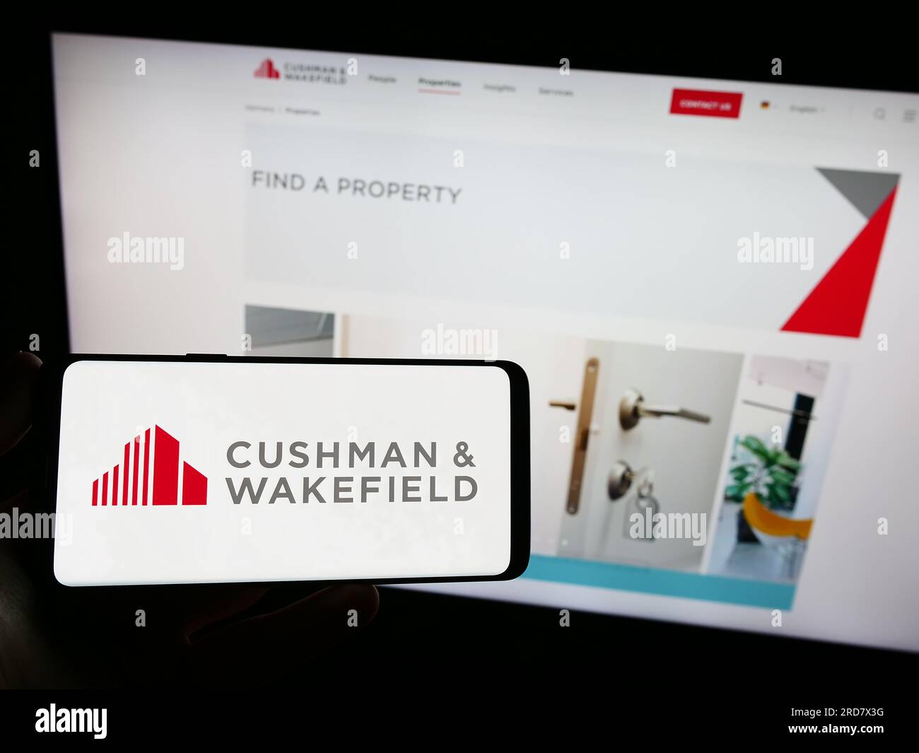 Personne détenant smartphone avec logo de la société immobilière Cushman Wakefield plc sur l'écran en face du site Web. Concentrez-vous sur l'affichage du téléphone. Banque D'Images