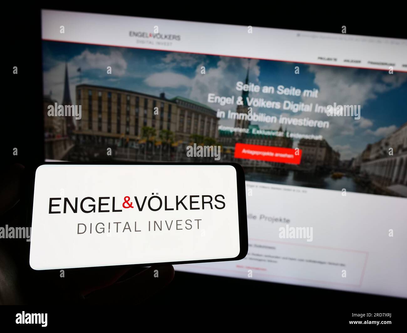 Personne détenant un smartphone avec le logo de la société immobilière allemande EV Digital Invest AG sur l'écran devant le site Web. Concentrez-vous sur l'affichage du téléphone. Banque D'Images