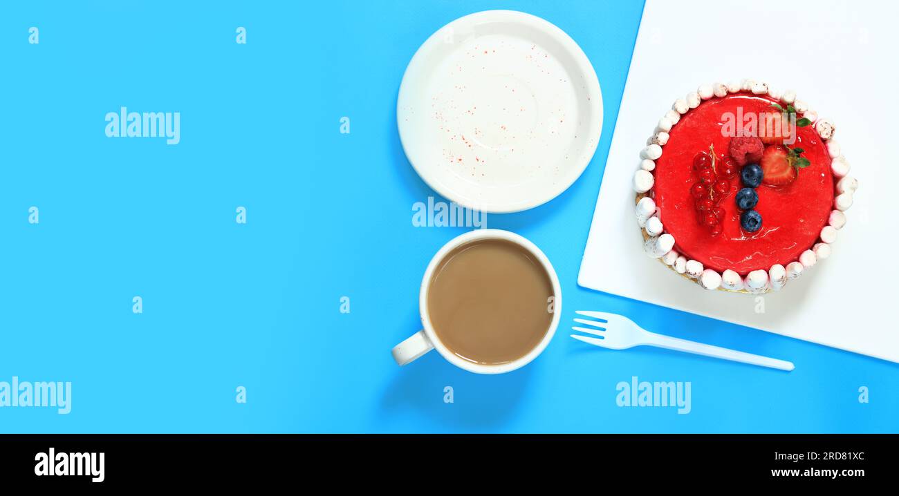 Petit gâteau aux baies et une tasse de café, vue de dessus, fond bleu. Douceur Banque D'Images