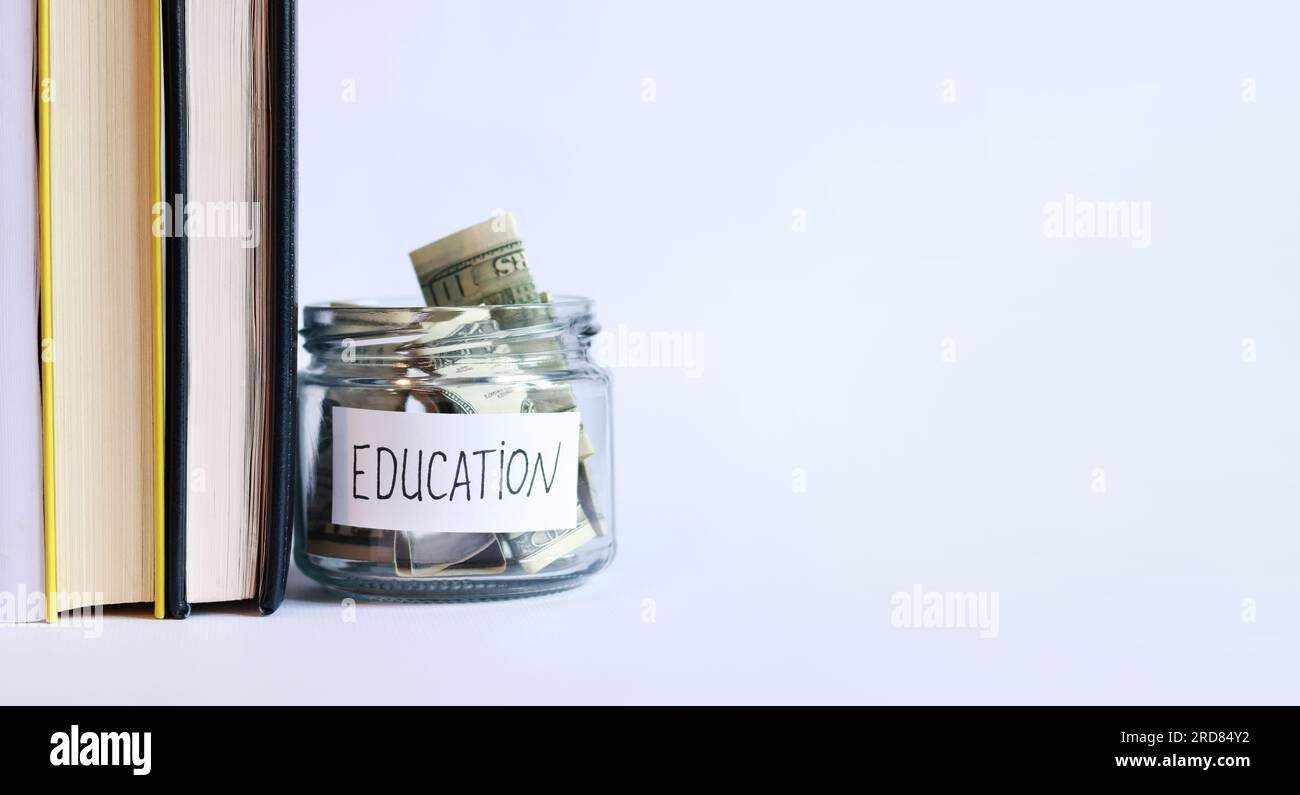 Pot en verre avec de l'argent près de la pile de livres. Tirelire avec des dollars pour l'éducation. Économisez de l'argent pour de futures études universitaires. Espace de copie Banque D'Images