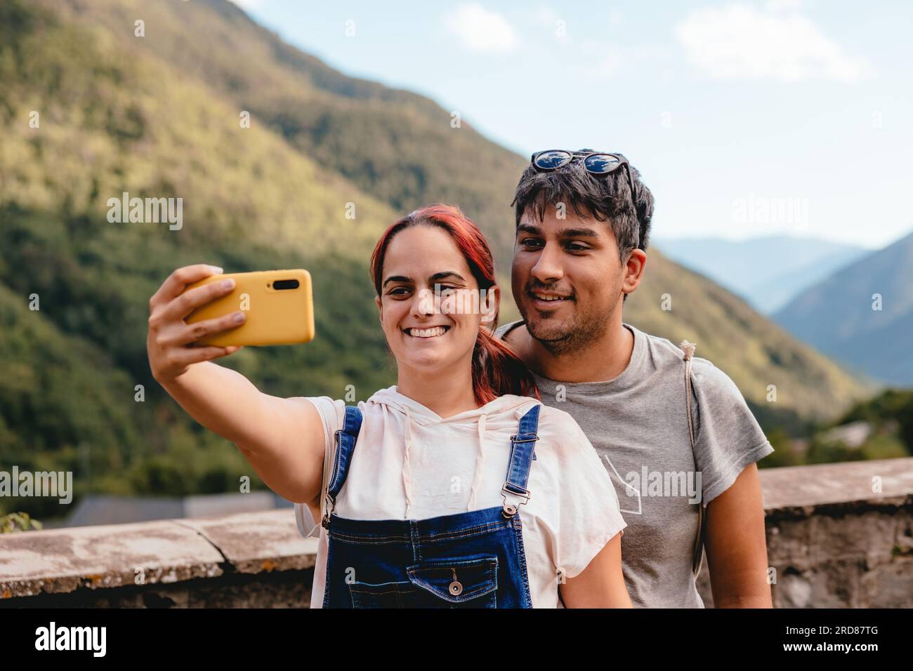 Jeune couple s'embrassant et prenant un selfie avec téléphone portable tout en faisant du tourisme rural dans un village de montagne. Voyage de vacances et vacances d'été en plein air i Banque D'Images