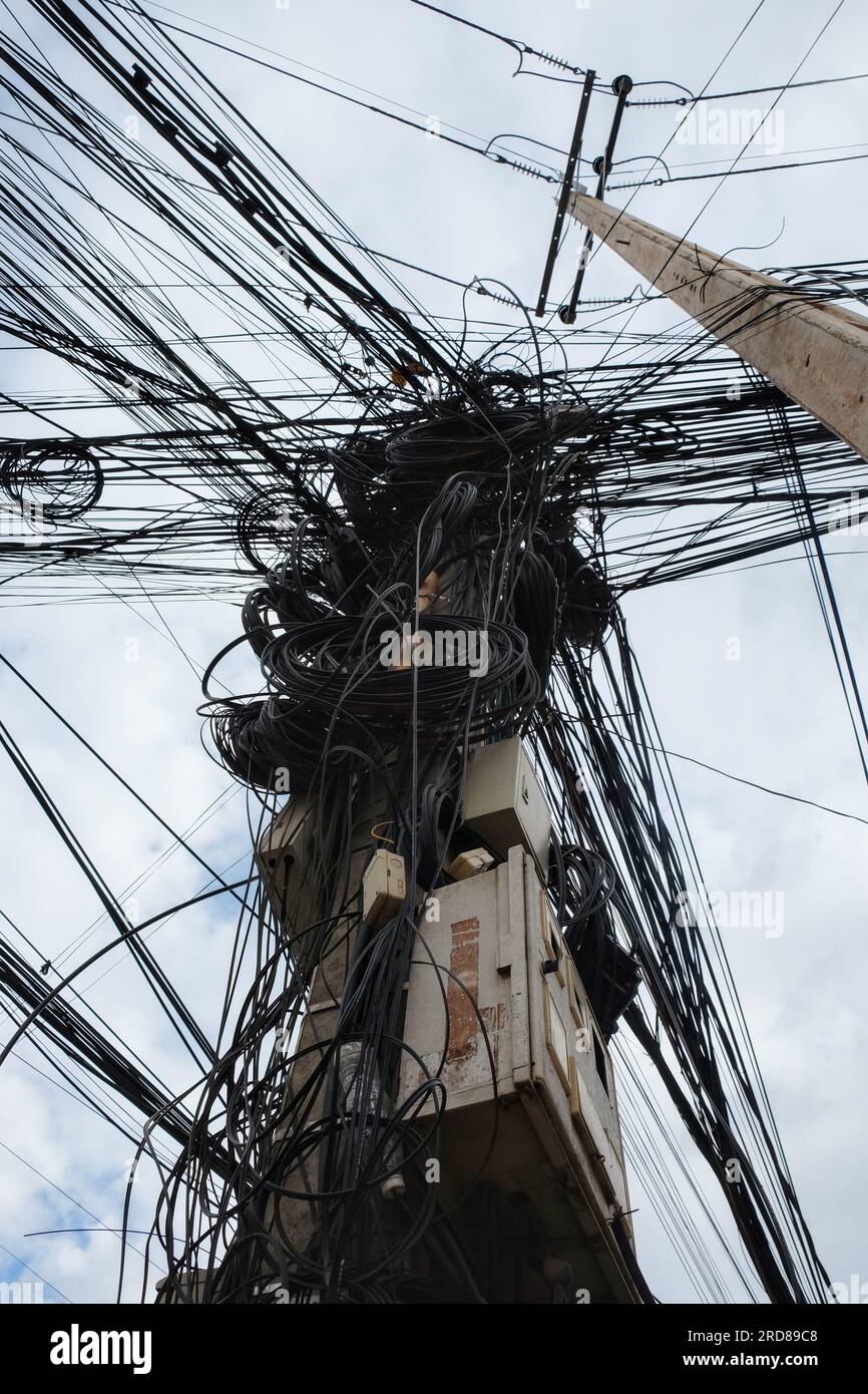 Une photographie capturant un réseau massif de câbles électriques enchevêtrés, illustrant la nature chaotique des réseaux électriques urbains en Asie. Banque D'Images