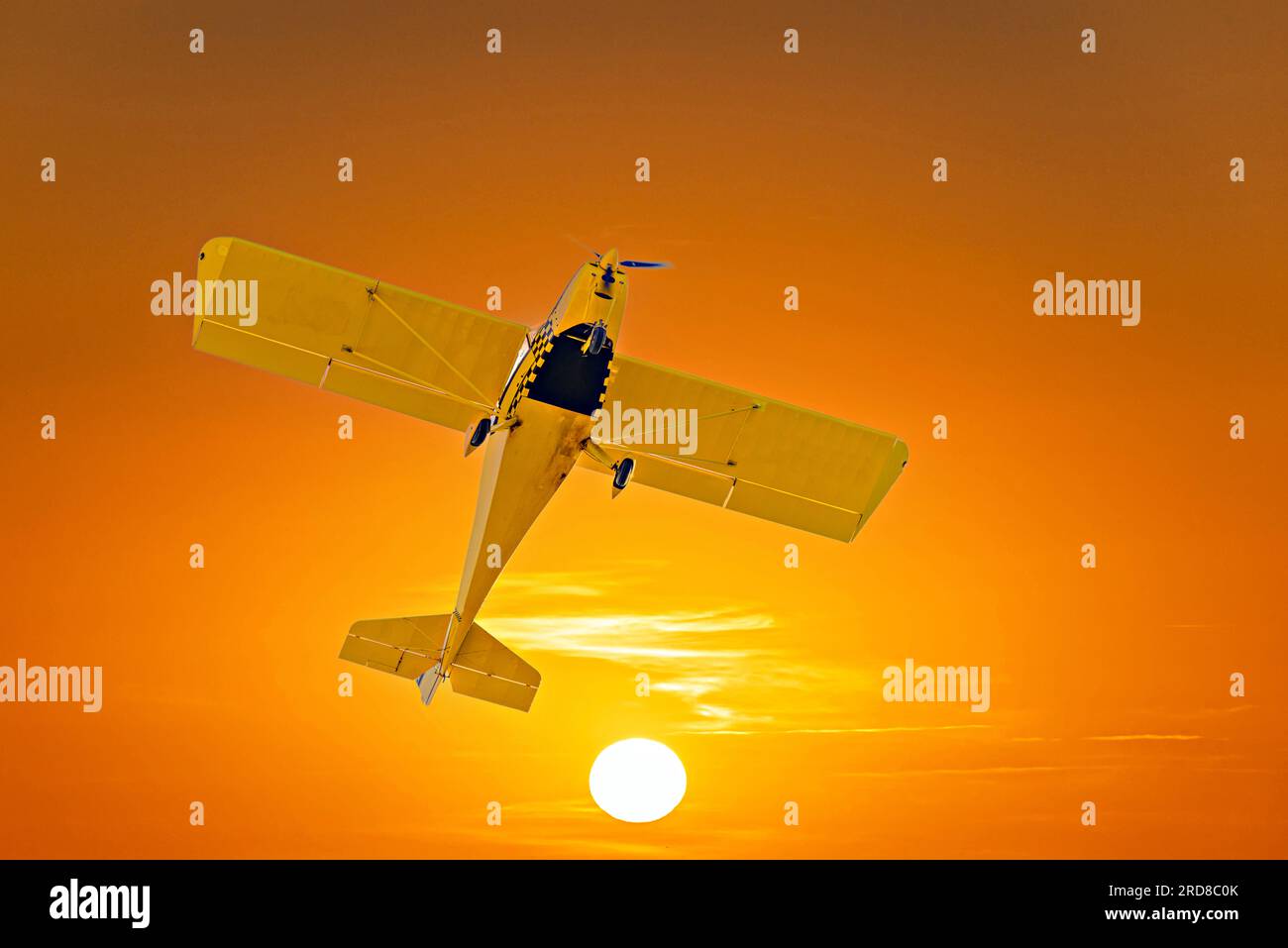 Un seul moteur avion ultraléger volant sous un ciel orange au coucher du soleil Banque D'Images
