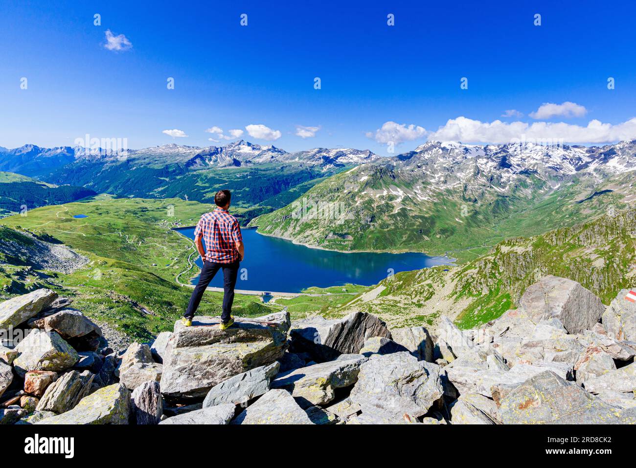 Un homme regardant le lac alpin de Montespluga debout sur des rochers, Madesimo, Valle Spluga, Valtellina, Lombardie, Italie, Europe Banque D'Images