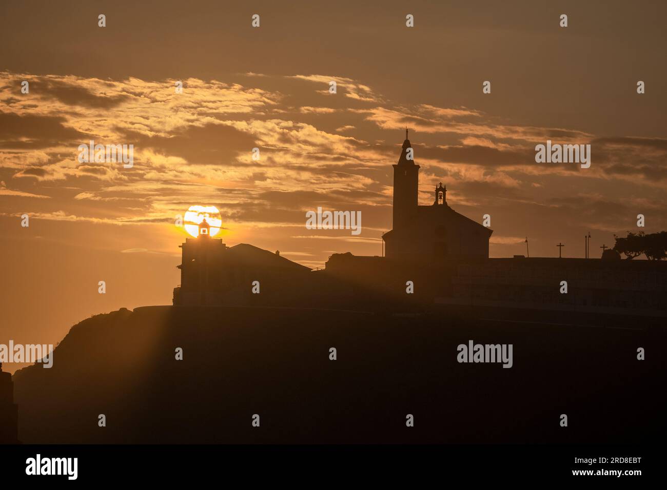 Soleil aligné avec la silhouette du phare et de l'église de Luarca, Asturies, Espagne, Europe Banque D'Images