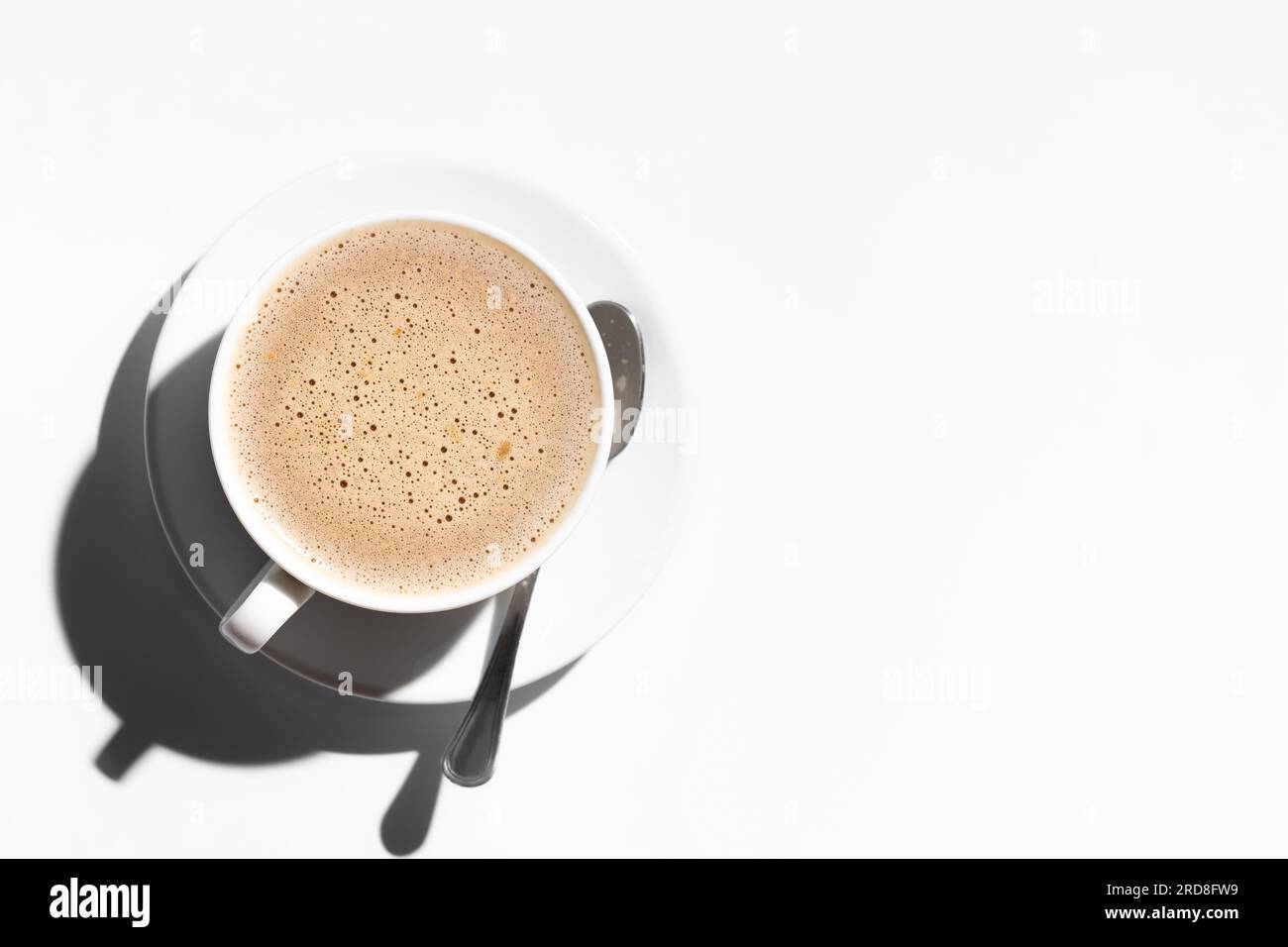 Tasse de cappuccino avec cuillère sur la plaque sur fond blanc Banque D'Images