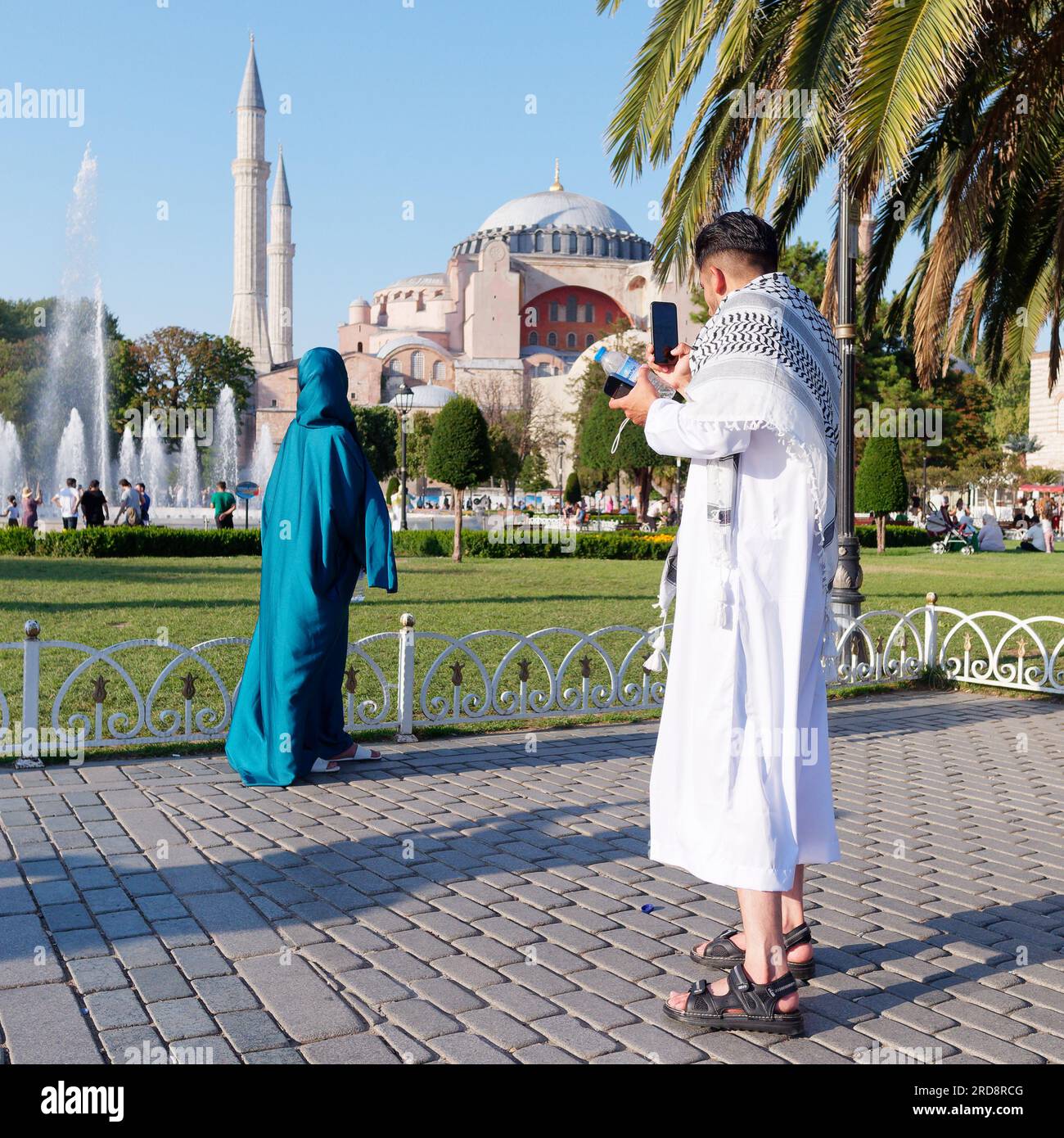 Un couple en robe traditionnelle profitant du parc Sultanahmet sur une soirée d'été avec la mosquée Sainte-Sophie derrière, Istanbul, Turquie Banque D'Images