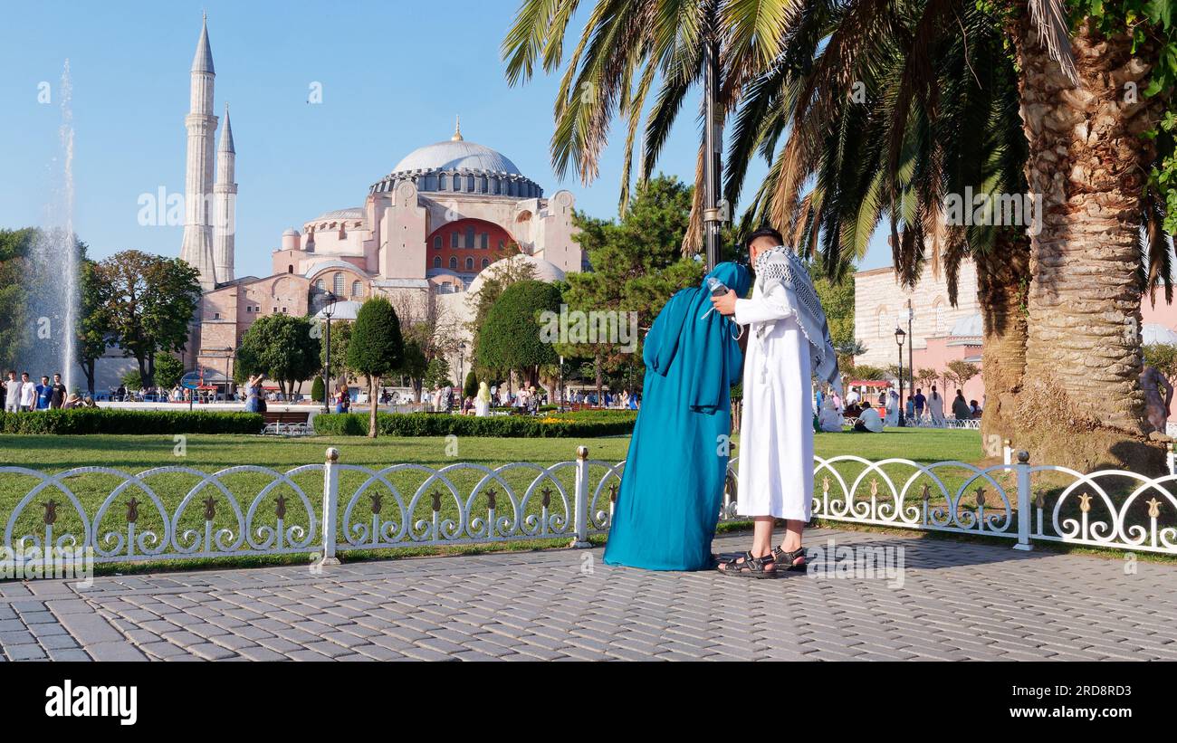 Un couple en robe traditionnelle profitant du parc Sultanahmet sur une soirée d'été avec la mosquée Sainte-Sophie derrière, Istanbul, Turquie Banque D'Images