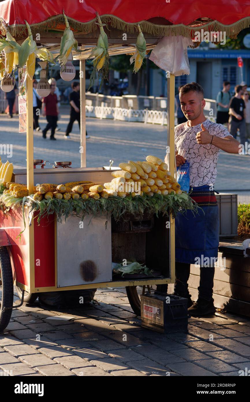 L'homme donne un signe pouce vers le haut alors qu'il vend du maïs d'un chariot rouge à Sultanahmet, Istanbul, Turquie. Banque D'Images