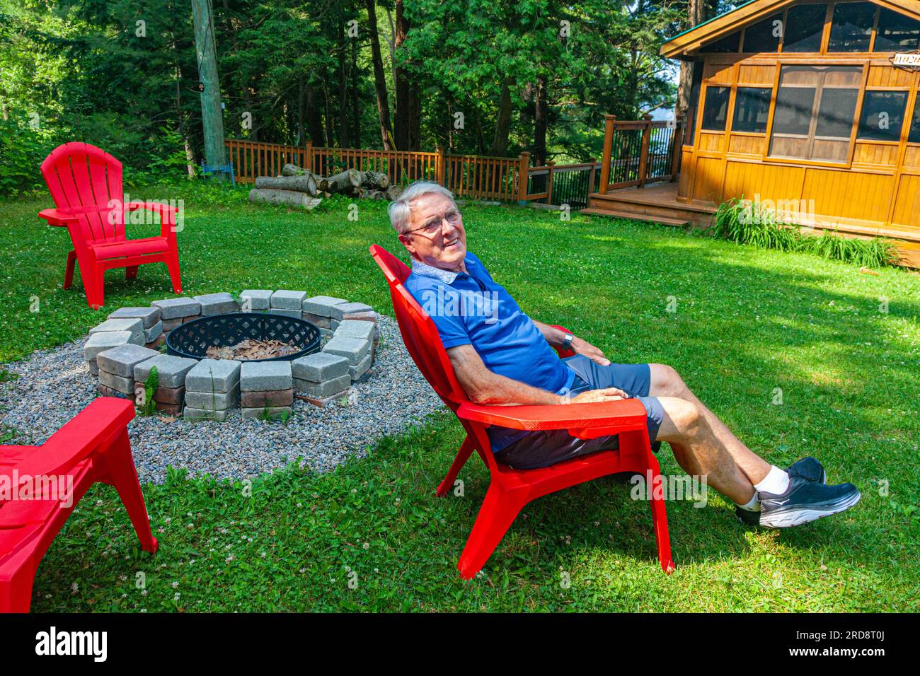 Figure de grand-père reposant dans une chaise rouge près du lac Sparrow à Muskoka Ontario Canada Banque D'Images