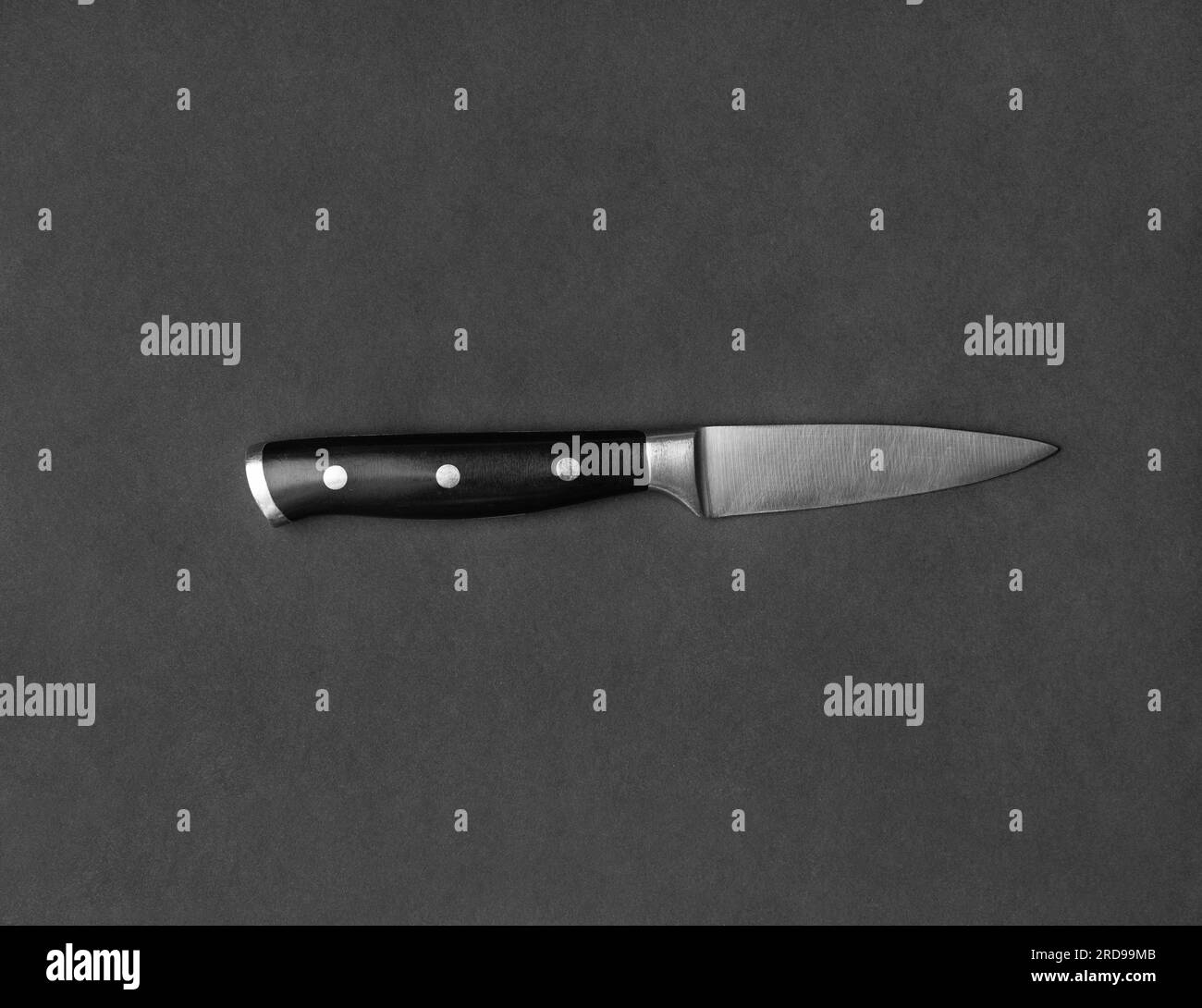 Couteau de cuisine avec poignée noire sur fond noir. Couteau sur fond sombre vue de dessus. Ustensiles de cuisine. Couteau à lame large. Banque D'Images