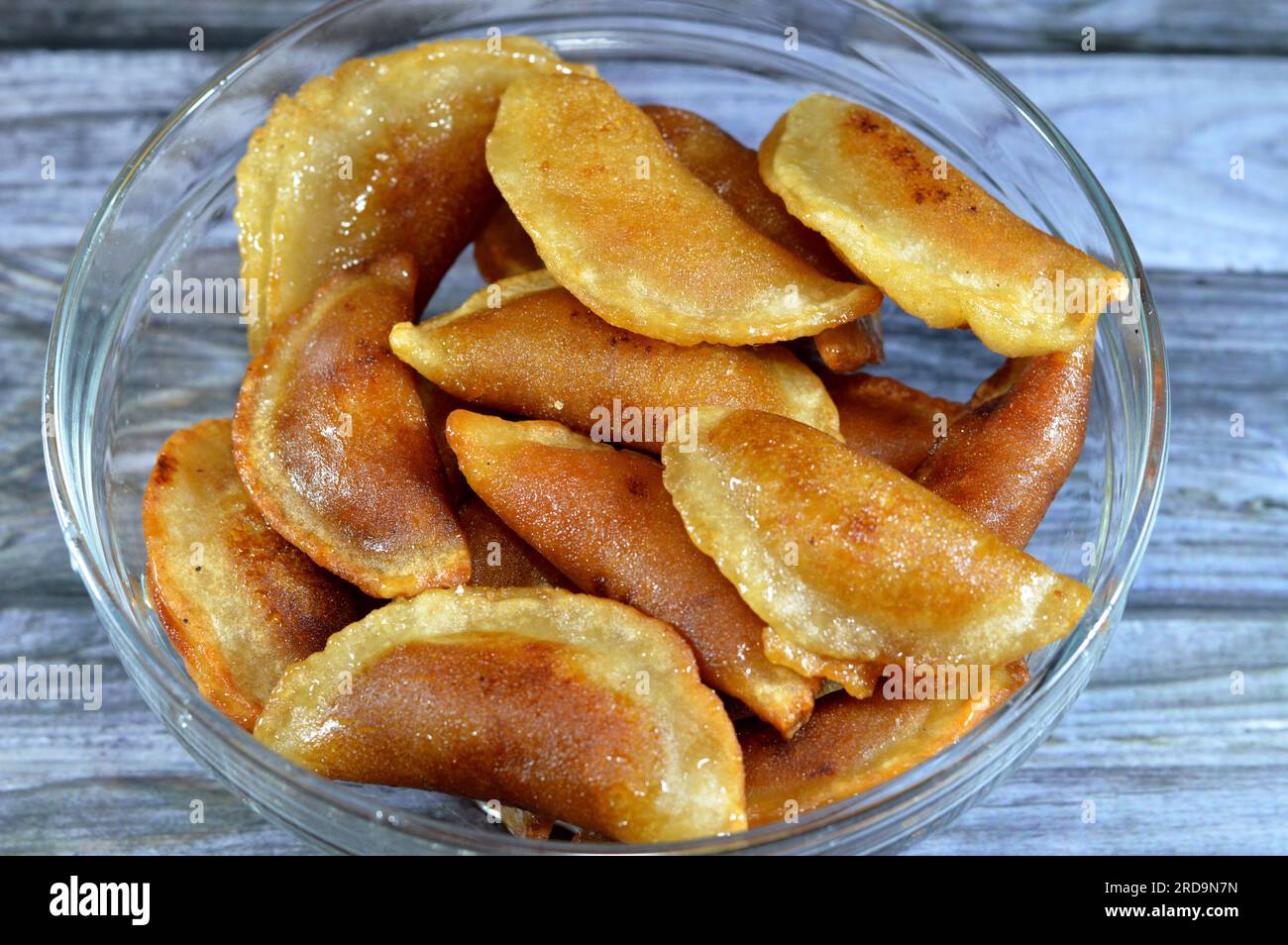 Un bol de boulettes de qatayef farcies et remplies de noix et de noix de coco râpées frits dans l'huile profonde et imbibées de sirop de sucre, dessert arabe plat plié Banque D'Images